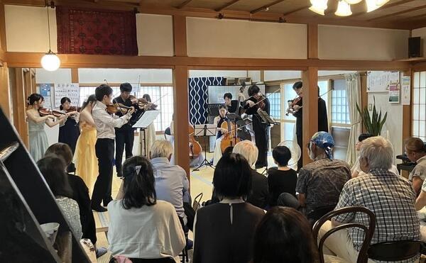 お寺の本堂で、合宿の成果を発表する演奏家たちと聴き入る人々